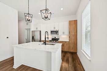 A modern kitchen with a white island and wooden cabinets at The Hadley - North Port, FL Apartments, Florida